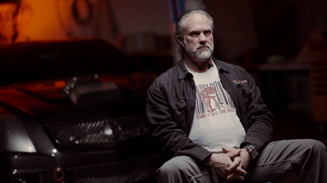 Devon Built founder in a dark garage wearing the She's Not For Sale graphic tee