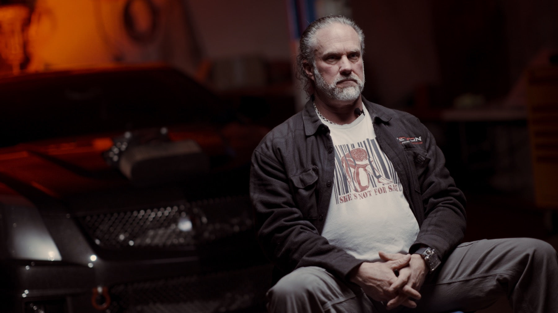Devon Built founder in a dark garage wearing the She's Not For Sale graphic tee